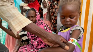 Un miembro del personal de MSF mide la circunferencia media del brazo (CMB) de Nouran Abdallah, de 2 años, quien huyó de El Fasher el 11 de octubre con su familia. La medición muestra desnutrición aguda moderada; será inscrita en el programa de la Clínica de Desnutrición Aguda Moderada en el campamento de desplazados de Dabaniera.