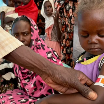 Un miembro del personal de MSF mide la circunferencia media del brazo (CMB) de Nouran Abdallah, de 2 años, quien huyó de El Fasher el 11 de octubre con su familia. La medición muestra desnutrición aguda moderada; será inscrita en el programa de la Clínica de Desnutrición Aguda Moderada en el campamento de desplazados de Dabaniera.