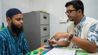 Un paciente con diabetes recibe atención médica. El médico de MSF le muestra una pluma de insulina.