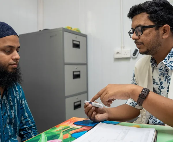 Un paciente con diabetes recibe atención médica. El médico de MSF le muestra una pluma de insulina.
