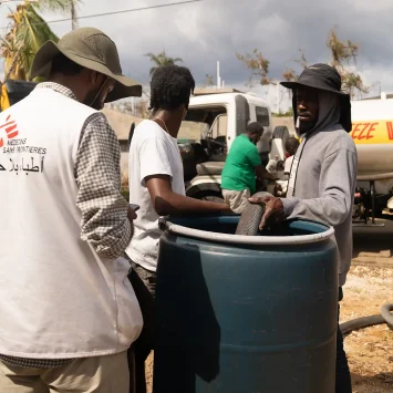 Lal Badshah, responsable de agua y saneamiento supervisa el llenado de un tanque de agua de 200 litros en la parroquia de Santa Isabel. La parroquia aún carece de electricidad y la infraestructura hídrica sigue interrumpida.
