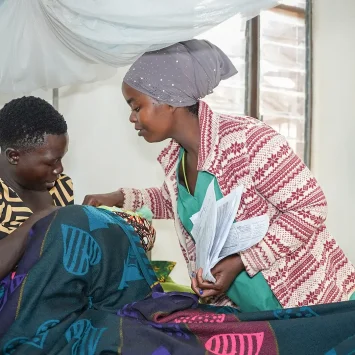 Una enfermera auxiliar de MSF y una madre atienden a un bebé en la sala de maternidad del hospital de MSF en el campo de Nduta.