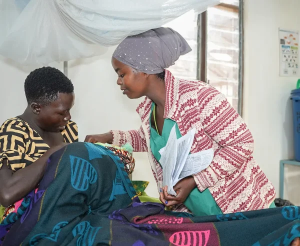 Una enfermera auxiliar de MSF y una madre atienden a un bebé en la sala de maternidad del hospital de MSF en el campo de Nduta.