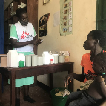 La enfermera de MSF Abau Susan entrega la medicación a una madre y le explica cómo y cuándo debe dársela a su hijo en el Centro de Atención Primaria del Ministerio de Salud en Kediba, Sudán del Sur.