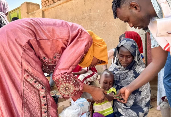 Un voluntario comunitario y un miembro del personal de MSF realizan un cribado MUAC, en Mohamed Ayoub, de 18 meses, inmediatamente después de su vacunación contra el sarampión.