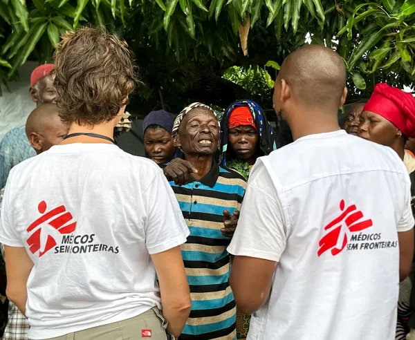 El personal de MSF Nathalie Gielen y Gimo Lazimo hablan con un grupo de personas desplazadas que esperan fuera de una clínica móvil de MSF en Alua Velha, distrito de Eráti, provincia de Nampula.