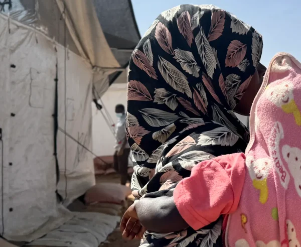 Amina* abraza a un niño frente a un refugio improvisado en Tawila. Mientras huía de El Fasher con sus hijos, fue violada por hombres armados. Estado de Darfur del Norte, Sudán, febrero de 2026. *Se ha utilizado un seudónimo para proteger su identidad.