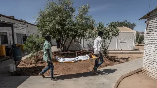 Dos trabajadores médicos de MSF transportan a un niño pequeño en una camilla desde el quirófano hasta la unidad de cuidados intensivos del Hospital París gestionado por MSF en Tawila.