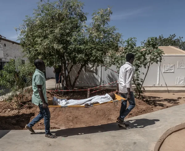 Dos trabajadores médicos de MSF transportan a un niño pequeño en una camilla desde el quirófano hasta la unidad de cuidados intensivos del Hospital París gestionado por MSF en Tawila.